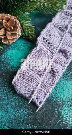 Handgefertigter Pullover. Strickmaterial aus Fliederfaden. Mit weihnachtlichem Hintergrund. Stockfoto