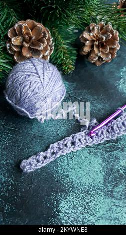 Handgefertigter Pullover. Strickmaterial aus Fliederfaden. Mit weihnachtlichem Hintergrund. Stockfoto