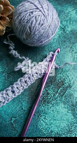 Handgefertigter Pullover. Strickmaterial aus Fliederfaden. Mit weihnachtlichem Hintergrund. Stockfoto