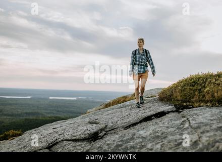 Junge Frau im Flanellhemd wandert entlang des Schoodic Mountain, Maine Stockfoto