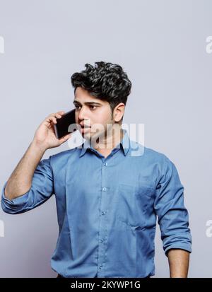 Ein gutaussehender Geschäftsmann in Formalitäten, ängstlich am Telefon, während er spricht Stockfoto