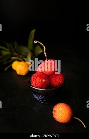 Arbutus, die Frucht des Erdbeerbaums, mit schwarzem Hintergrund Stockfoto