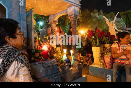 Frauen sitzen an einem Grab auf dem Xochimilco Friedhof, der für den Tag der Toten dekoriert wurde, oder Dia de los Muertos in Oaxaca, Mexiko. Stockfoto