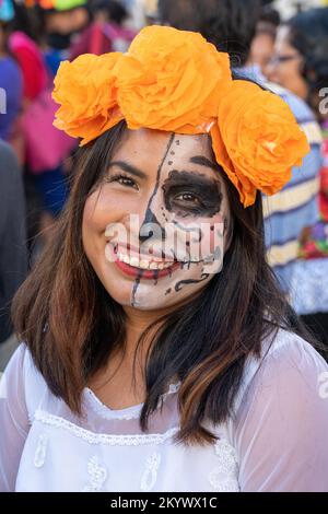 Eine junge Frau, deren Gesicht für die Todestag-Feier in Oaxaca, Mexiko, gemalt wurde. Stockfoto