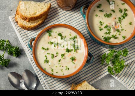 Hausgemachte cremige Muschelsuppe mit Brot und Petersilie Stockfoto