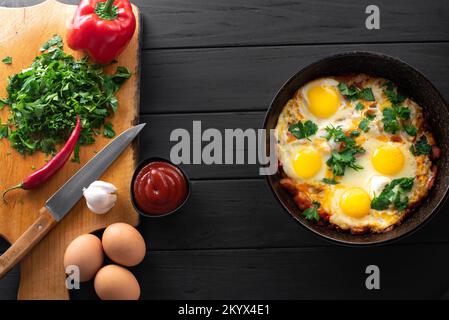 Vegetarisches Rührei in einer Pfanne. Eier und Gemüse. Hausgemachte rustikale Spiegeleier mit Tomaten und Petersilie im Topf Stockfoto