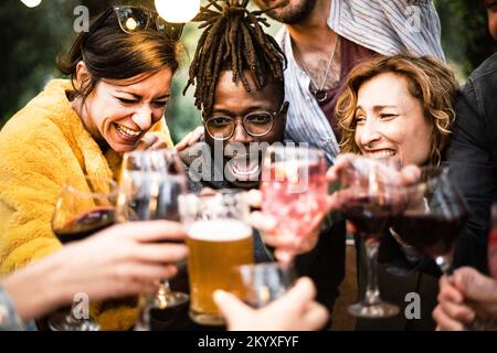 Echte Freunde feiern den Geburtstag eines afroamerikanischen Mannes zu Hause - eine Gruppe junger Leute, die Spaß zusammen in der Happy Hour im Pub haben Stockfoto