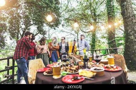 Eine große Gruppe von Freunden wartete auf eine Dinnershow auf dem Land, während sie über Sommerreisen sprachen Stockfoto