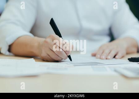 Nahaufnahme. Männliche Hände am Tisch, schreiben mit einem Stift auf Papier, unterschreiben Dokumente, schließen einen Vertrag, füllen einen Fragebogen aus, schreiben einen Brief. Stockfoto
