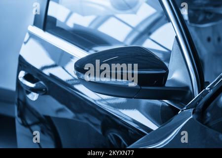 Nahaufnahme des schwarzen Seitenspiegels des modernen Autos in der Autowerkstatt Stockfoto