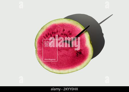 Farbe des Jahres 2023 Viva Magenta. Halb reife frische Wassermelone mit Löffel in Farbe des Jahres 2023 Viva Magenta. Stockfoto