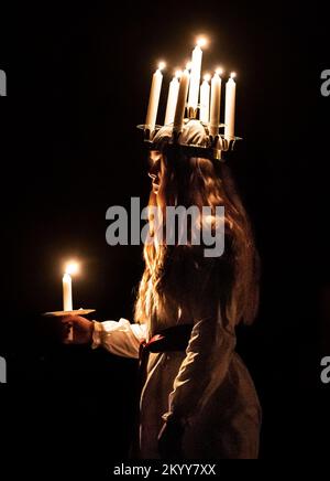 Clara Nordin trägt eine Krone aus Kerzen, die die Heilige Lucy symbolisiert, während sie die Feier von Sankta Lucia anführt. Sie basiert auf dem Mut und dem Märtyrertum eines jungen sizilianischen Mädchens St. Lucy, das im frühen 4. Jahrhundert während des Festival of Light im York Minster starb. Foto: Freitag, 2. Dezember 2022. Stockfoto