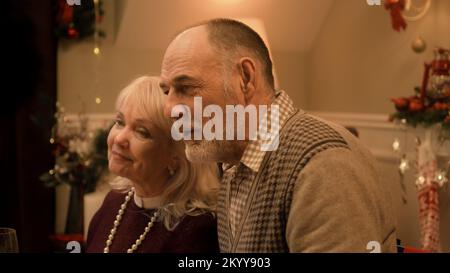 Glückliches Seniorenpaar, das lacht und mit der Familie redet. Großeltern feiern Weihnachten oder Neujahr 2023. Warme Atmosphäre beim Weihnachtsessen mit der Familie zu Hause. Weihnachtsdekoration. Stockfoto