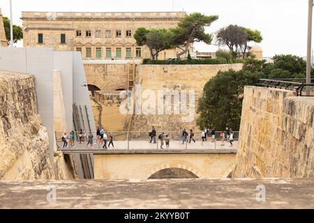 Valletta, Malta - 12. November 2022: Menschen überqueren die Fußgängerbrücke am Haupttor der Stadt, das im Projekt Renzo Piano rekonstruiert wurde Stockfoto