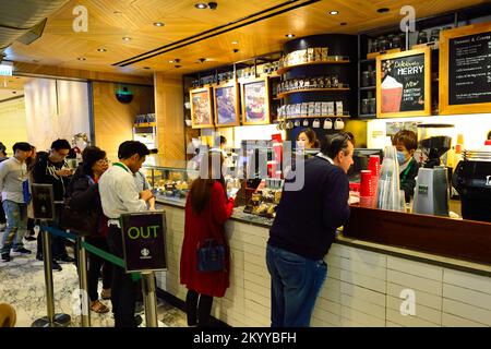 HONGKONG - 25. DEZEMBER 2015: Gäste des Starbucks Cafés. Die Starbucks Corporation ist ein amerikanisches globales Kaffeeunternehmen und eine Kaffeehauskette mit Sitz in Stockfoto