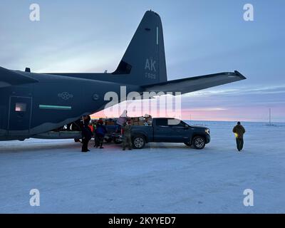 Freiwillige bei der Alaska Nationalgarde, der Heilsarmee und lokalen Gemeindepartnern laden Geschenke für die Operation Santa Claus aus aus einem 176.. Flügel HC-130J Kampfflugzeug King II am Nuiqsut Flughafen ab, 29. November 2022. Die Operation Santa Claus ist das alljährliche Programm der Alaska National Guard für die Zusammenarbeit und Unterstützung der Gemeinschaft, das Kindern in entlegenen Gemeinden im ganzen Bundesstaat Geschenke überreicht. In Zusammenarbeit mit der Heilsarmee lieferten der Weihnachtsmann, Frau Claus und mehr als drei Dutzend Elfen 1.420 Pfund Geschenke, Rucksäcke, Hygieneartikel und Bücher an 191 Kinder in Nuiqsut. Alaska Nationalgarde Stockfoto