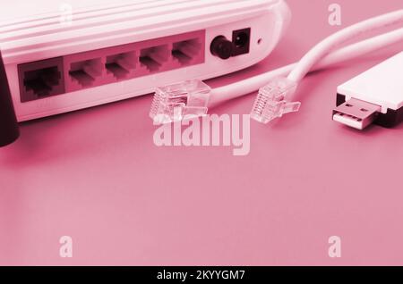 Internet-Router, tragbarer USB-wi-Fi-Adapter und Internetkabelstecker liegen auf hellem orangefarbenen Hintergrund. Für die Internetverbindung erforderliche Elemente Bild in Viva Magenta, Farbe des 2023. Jahres Stockfoto