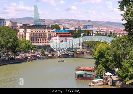 Tiflis, Georgia - 07 23 2022 Uhr: Sommertag: Luftaufnahme über den Fluss Mtkvari Kura in der Hauptstadt von Georgia Tiflis mit Friedensbrücke Stockfoto