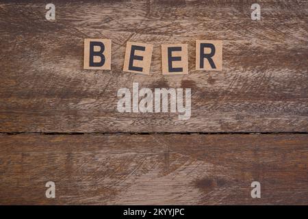 Schild mit kleinen hölzernen Buchstaben mit dem Wort Bier auf rustikalem Holzhintergrund. Stockfoto