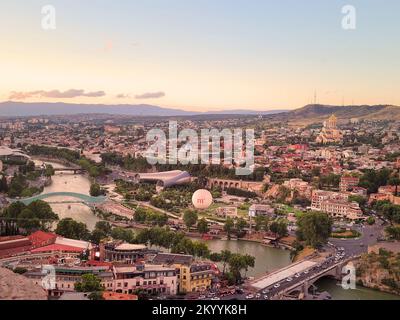 Tifisi, Georgia - 07 23 2022: Sommerpanorama bei Sonnenuntergang von Tiflis, der Hauptstadt Georgiens mit Straßen der Altstadt von Tifisi im Vordergrund, Mtkvari Stockfoto