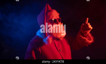Porträt des Weihnachtsmannes in Sonnenbrille im Neonlicht. Stockfoto