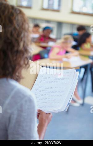 Ich bereichere eifrige junge Köpfe. Eine Schulteransicht eines Lehrers, der Schülermarkierungen ausliest. Stockfoto