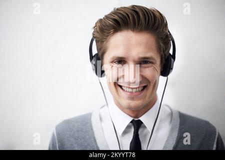 Musik macht alles besser. Ein attraktiver junger Mann, der Musik über seine Kopfhörer hört. Stockfoto