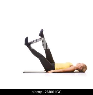 Sie liebt ihren Pilates-Ring. Eine hübsche, junge Blondine, die sich die Beine mit einem Pilates-Ring ausarbeitet. Stockfoto