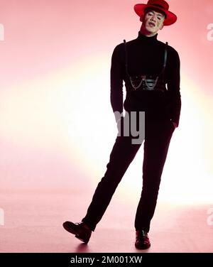 Mode, luxuriöser Trend und Mann, der auf einem pinkfarbenen Studiohintergrund für ästhetischen Stil posiert. Kreativer, Model und modischer Typ mit coolem, teurem Stockfoto