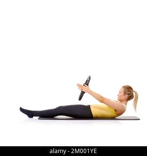 Roll-Up-Übung. Eine hübsche, junge Blondine, die die Roll-Up-Übung mit ihrem Pilates-Ring durchführt. Stockfoto