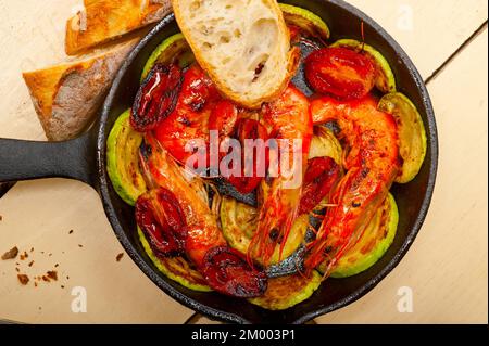 Geröstete Garnelen auf gusseiserner Pfanne mit Zucchini und Tomaten Stockfoto