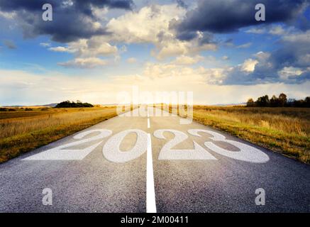 2023 geschrieben auf einer Autobahn inmitten einer leeren Asphaltstraße und einem wunderschönen blauen und bewölkten Himmel. 2023 Idee für das neue Jahr. Keine Leute, niemand. Stockfoto