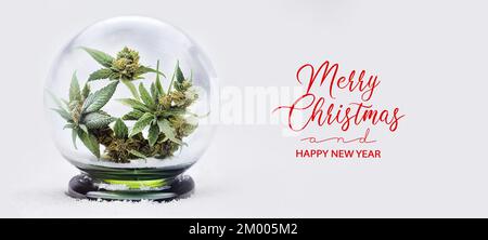 Weihnachtliches Cannabisbanner. Weihnachts- und Neujahrskarte mit Marihuana-Hanf in einem Glas Schneekugel mit Schneeflocken und Schnee Stockfoto