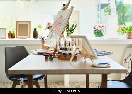 Interieur des Künstlerstudios mit Leinwand, Pinsel, Farbtupfer auf Holztisch. Malerraum mit Werkzeugen und Zubehör Stockfoto