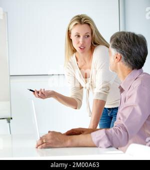 Designideen austauschen... zwei Designer arbeiten gemeinsam an einem Notebook und sprechen miteinander. Stockfoto