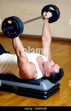 Er hält seine Brustmuskeln in perfekter Form. Ein attraktiver Sportler im Fitnessstudio, der Sport macht. Stockfoto