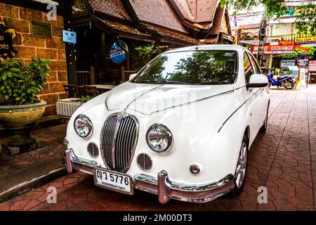 Ein weißer Jaguar parkt am Bürgersteig in der Altstadt von Bangkok. Stockfoto