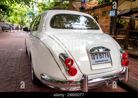 Ein weißer Jaguar parkt am Bürgersteig in der Altstadt von Bangkok. Stockfoto