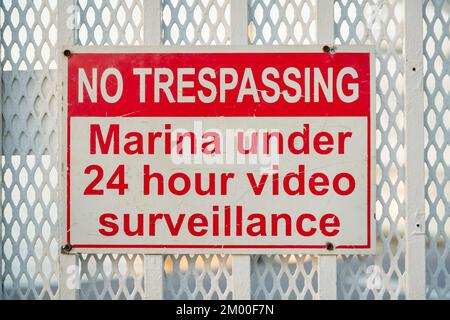 Destin, Florida - kein Trespassing, Marina unter 24 Stunden Videoüberwachung Schild. Nahaufnahme eines Schildes auf den lackierten Metallgeländern mit Edelstahlausdehnung Stockfoto