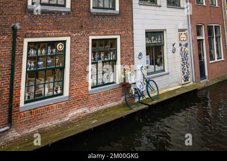 Malerischer Blick auf ein typisch holländisches Kanalhaus, wo typische Delfteller namens „Delft Blue“ (Holländisch: Delfts Blauw) in den Fenstern zu sehen sind. Stockfoto