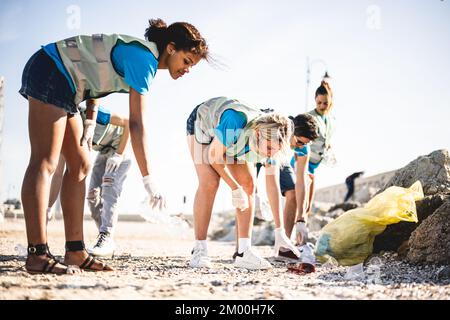 Verschiedene Leute, die den Strand säubern, Freiwillige, die den Abfall an der Küste sammeln, junge Leute, die in einem Team arbeiten, die sich der Verschmutzung bewusst sind Stockfoto