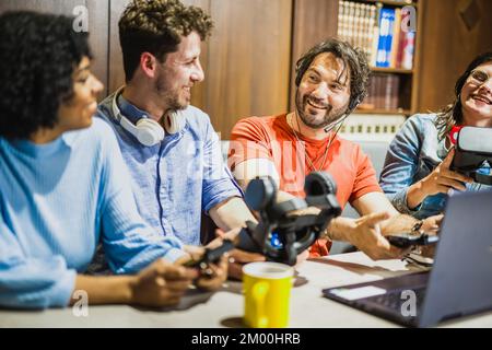 Gruppe junger Influencer, die ihren Live-Streaming-Kanal in sozialen Medien nutzen, um neue Headsets für virtuelle Realität zu prüfen, vier Personen sprechen auf Inte Stockfoto