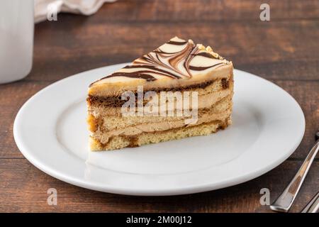 Ein Stück weiße Schokolade und Karamellkuchen auf einem Holztisch Stockfoto