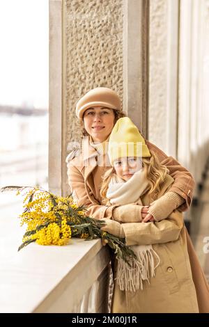 Porträt von Mutter und Tochter mit Mimosenstrauß im Frühlingspark. Frühling, Internationaler Frauentag 8. März. Stockfoto