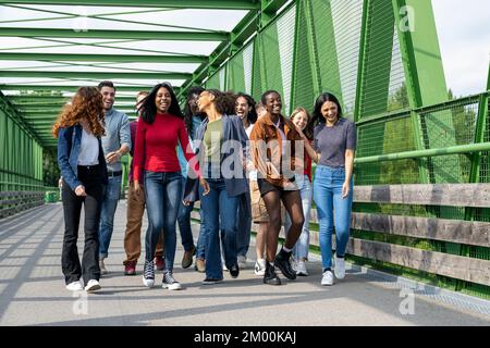 Große Gruppe von Menschen der Z-Generation, junge Universitätsstudenten, die spazieren gehen und Spaß im Freien in einem Stadtpark haben Stockfoto