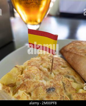 Typisch spanisches Gericht namens Tortilla de patatas mit Flagge spaniens und einem Glas Bier Stockfoto