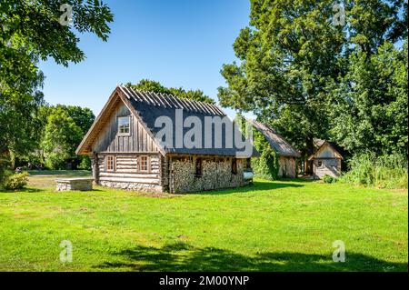 Ein Beispiel für die Holzarchitektur der Insel Ruhnu. Holzhaus mit gestapeltem Brennholz. Brennholz, das im Winter zum Heizen geerntet wurde. Stockfoto