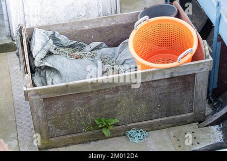 Bild: Seil, Fischnetz und orangefarbener Eimer in der Holzbox des Fischerboots Stockfoto