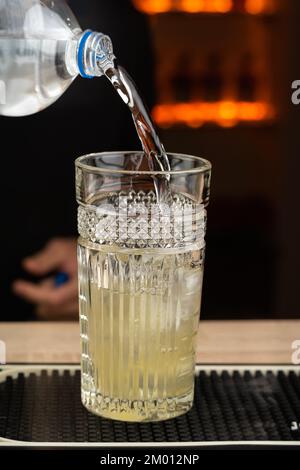 Barkeeper gießt Wasser in ein Cocktailglas an einem wunderschönen Abend. Speicherplatz kopieren Stockfoto