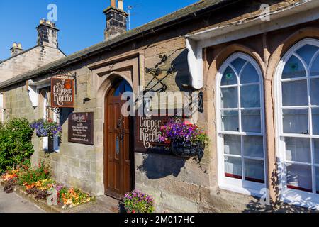 The Copper Kettle, traditionelle Teestube in Bamburgh, einem Dorf im Northumberland an der Nordostküste an einem sonnigen Tag mit Blumen und Hängekörben Stockfoto